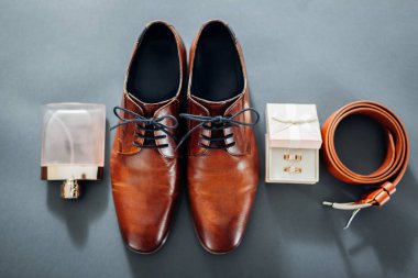 Damat düğün günü aksesuarları. Kahverengi deri ayakkabı, kemer, parfüm, altın yüzük. Erkek moda