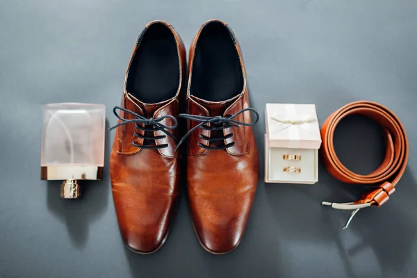 Bruidegom bruiloft dag accessoires. Bruin lederen schoenen, riem, parfum, gouden ringen. Mannelijke mode — Stockfoto