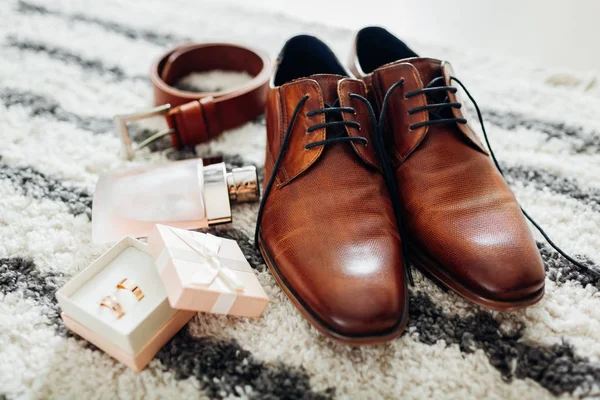 Bruidegom bruiloft dag accessoires. Bruin lederen schoenen, riem, parfum, gouden ringen. Mannelijke mode — Stockfoto