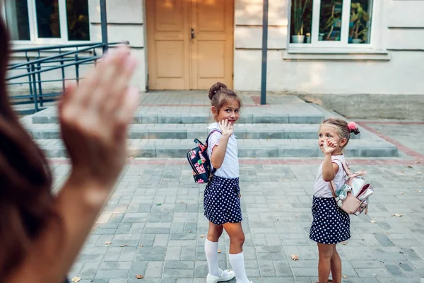 Jeune mère saluant ses filles avant que les classes à l'extérieur de l'école primaire ne les voient partir. Famille dire au revoir . — Photo