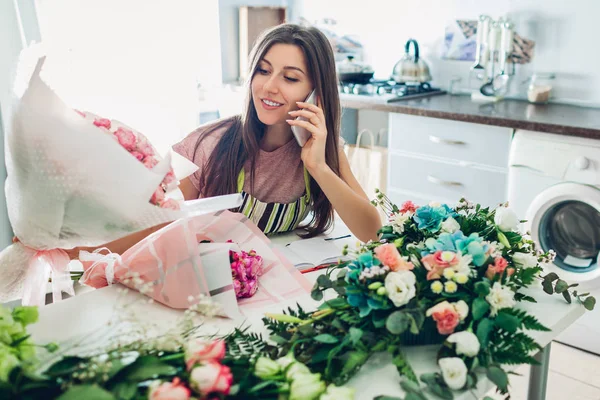 花艺妇女创造花组成在家里。工人组成花束，并与客户通过电话交谈. — 图库照片