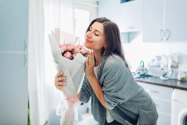 Mujer oliendo ramo de rosas. Ama de casa disfrutando de la decoración e interior de la cocina. Dulce hogar — Foto de Stock