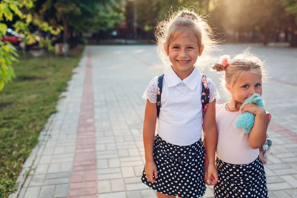 Jolies sœurs filles portant des sacs à dos et tenant la main. Enfants élèves séjournant en plein air école primaire . — Photo