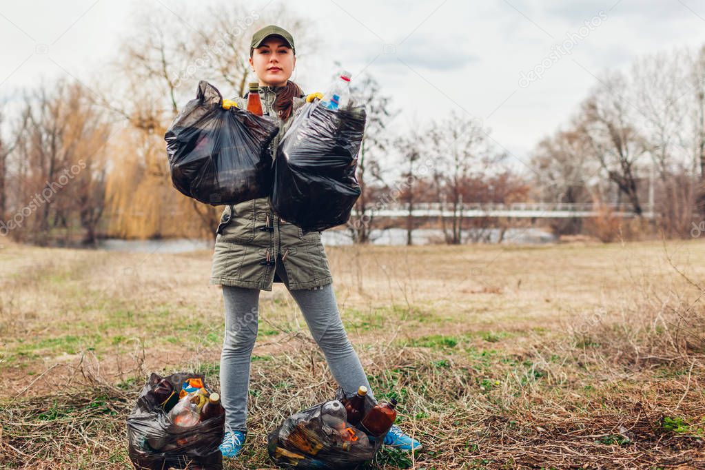 Litter picking. Woman volunteer cleaning up the trash in park. Picking up garbage outdoors. Ecology and environment