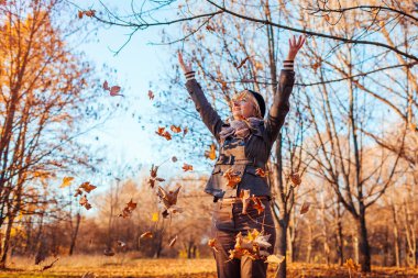 Sonbahar. Sonbahar ormanına yaprak atan orta yaşlı bir kadın. Yaşlı kadın dışarıda eğleniyor