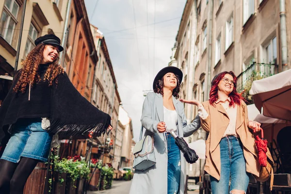 Девочки разговаривают и веселятся. Уличная фотография трех молодых женщин, идущих по городской улице . — стоковое фото