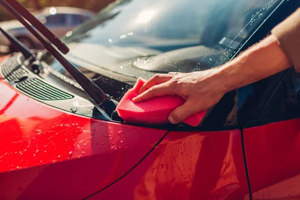 Car washing. Man cleaning car with soapy sponge outdoors. Close-up