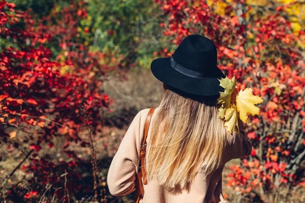 Autumn vibes. Young woman walking in autumn forest among red leaves. Traveller admires nature — Stock Photo, Image