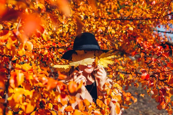 Φθινοπωρινή διασκέδαση Νεαρή γυναίκα που περπατάει στο δάσος του φθινοπώρου καλύπτοντας τα μάτια με φύλλα. Κορίτσι που διασκεδάζει — Φωτογραφία Αρχείου