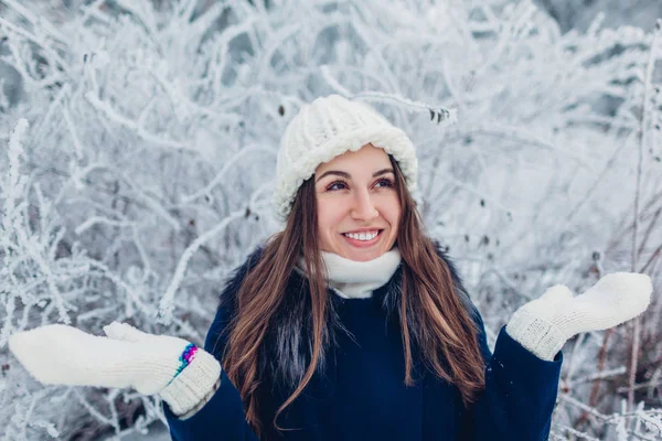 Kış aktiviteleri. Kış parkında yürüyen genç bir kadın kar ve soğuğa hayran. Kız dışarıda eğleniyor..