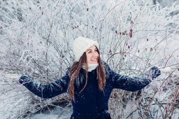 Attività invernali. Giovane donna che scuote rami con gelo e neve nella foresta invernale. Ragazza divertirsi all'aperto . — Foto Stock