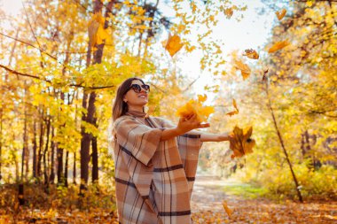 Sonbahar sezonu. Sonbahar ormanında yaprakları atan bir kadın. Genç bayan dışarıda eğleniyor.