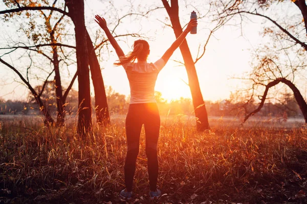 Futó felemelte karját edzés után érzés szabad és boldog sikerült edzés. A nő csodálja a naplementét. — Stock Fotó