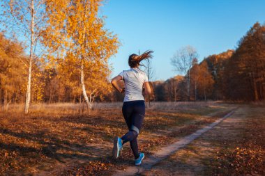 Koşu antrenmanı ve sonbahar parkında egzersiz. Gün batımında koşan kadın. Aktif sağlıklı yaşam tarzı