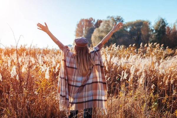 Autumn fashion. Young woman wearing stylish poncho outdoors. Clothing and accessories. Happy girl raising hands — Stock Photo, Image