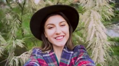 Genç bir kadın, yaz bahçesinde çiçek açan tamarisk çalılarının yanından geçiyor. Mutlu kız göz kırparak gülüyor. Parkta kendini filme çekiyor.