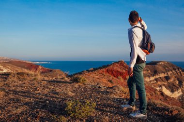 Santorini Adası 'ndaki White Beach' te yürüyen yürüyüşçü Yunanistan 'ın deniz manzarasının tadını çıkarıyor. Sırt çantalı bir adam seyahat ediyor. Yaz tatili