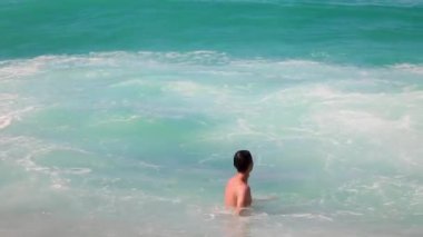 Denizde yüzen yakışıklı adam. Üstsüz seksi adam dalgalara atlıyor, eğleniyor. Yaz tatili