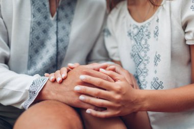 Yeni evli çiftin el ele tutuşması. Gelin ve damat geleneksel işlemeli Ukrayna gömlekleri giyerler. Kapat.