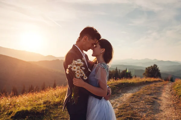 Mutlu çift gün batımında dağlarda sarılırken. Yazın Karpatlar 'da genç gelin ve damadın portresi.