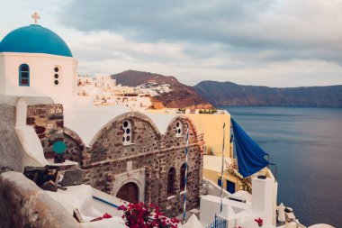 Santorini Adası Oia Günbatımı Caldera manzarası. Geleneksel beyaz evler ve deniz manzaralı mavi çatı mimarisi olan kilise. Yunanistan 'a Seyahat.