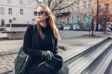 Sokak ortasında merdivenlerde oturan şık bir genç kadının portresi. Sonbahar giysileri, aksesuarlar. Kadın modası..