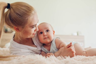 Yatakta bebeğiyle yatan bir kadın. Annesine sarılan çocuk. Aile evde birlikte vakit geçiriyor.