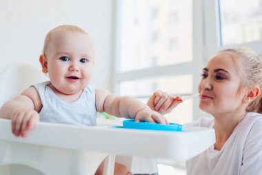 Anne küçük bebeği meyvelerle besliyor. Aile yemeği. Çocuklar için sandalyede oturan bebek. Yaşam biçimi