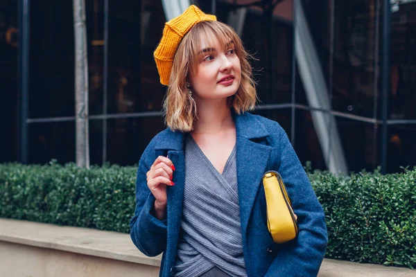 黄色のベレー帽をかぶったスタイリッシュな若い女性の肖像画は屋外で財布を保持する 秋のファッション女性アクセサリーや服 トレンディな古典的なブルーの衣装 — ストック写真