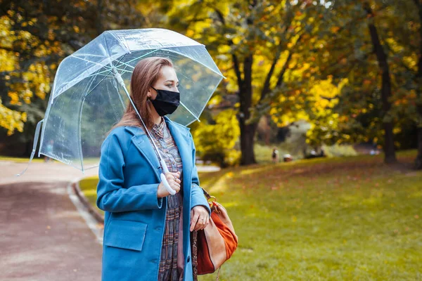 Стильная Молодая Женщина Защитной Маске Гуляет Осеннем Парке Прозрачным Зонтиком — стоковое фото