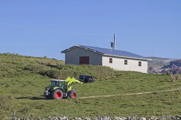 Farmer with tractor does his job on the plateau of the Monti Lessin mountains