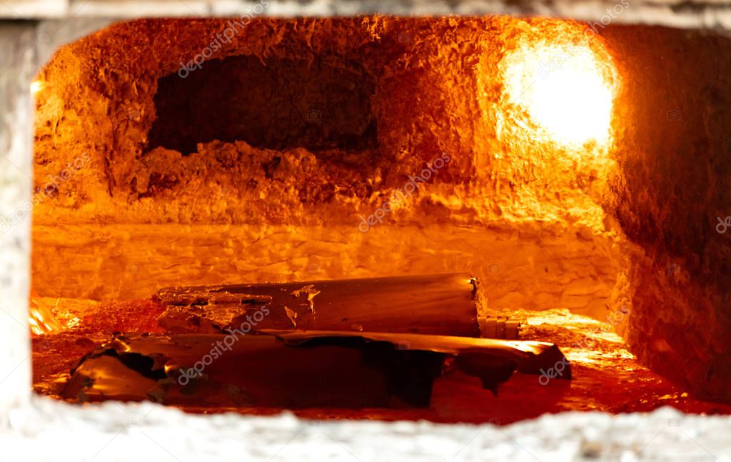 looking inside an aluminum melting furnace, in a foundry, with liquid and solid pieces of metal