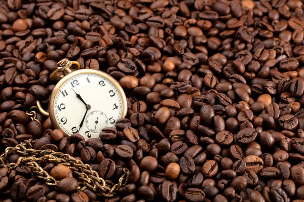 a lot of coffee beans with an old hand watch, conceptual photo indicating that it is time for a good coffee