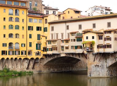 Ponte Vecchio Köprüsü iki tarafında inşa sarı boyalı evleri ile Floransa'da Arno Nehri üzerinde görünümü
