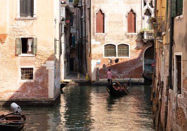 Bir gondol Venedik binalarda eski duvarları arasında dar bir kanal gider, adam kırmızı soyulmuş gömlek giymek