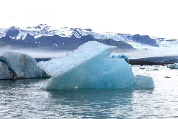 冰川的一块蓝色冰漂浮在水面上 背景是山脉和冰川 — 图库照片