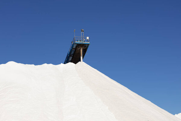 mountain of white salt on blue sky, salt extraction process and piled up