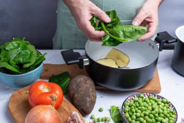 Pişirmek için diğer sebzelerin yanında ıspanak yaprakları götürmek..