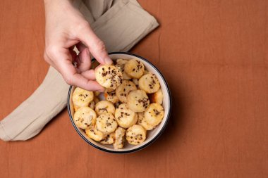 Ev yapımı peynirli kurabiyeyi komposto tabağından alan elin en üst görüntüsü..