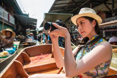 Genç kadın fotoğraf ile fotoğraf makinesi portresi açık yaz seyahat, kayan bir pazarda rahat bir şekilde resim yapma.