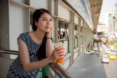Asyalı kadın kısa köprünün yanında yerel süt çay onun elinde tutan şehir yolda mola.