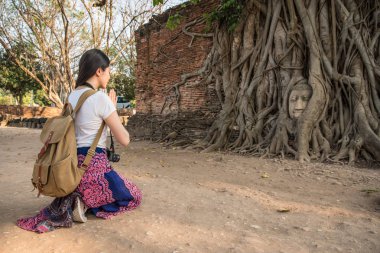 Asyalı kadın yolun yanında ve dua önüne çökmüş. İçinde rahat giyiyor. 