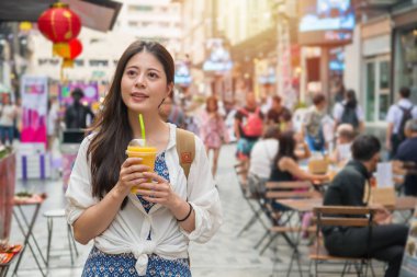 Mango suyu bir fincan tutarak ve aynı zamanda pazarda alışveriş sokak pazarında yürüyüş Asyalı kadın.