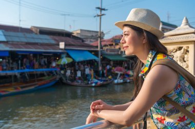 Asyalı kadın turist vücudu üzerinde bariyer eğildi ve muhteşem güneş ışığı altında yüzen pazarı manzarasının keyfini çıkarın.