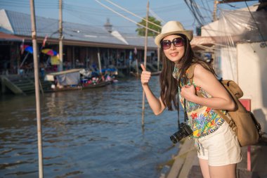 Nehir kıyısında duran ve büyük bir poz Asyalı kadın başparmak ve fotoğraf çekmek için kameraya bak.
