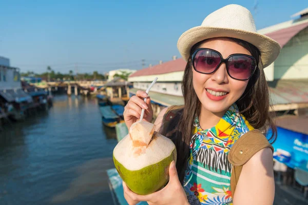 Asyalı kadın içecekler ısısı bu şiddetli güneş ışığı altında sakin için Hindistan cevizi içmek.