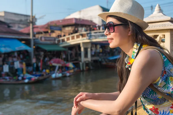 亚洲女性游客把她的身体靠在栅栏上 在灿烂的阳光下欣赏浮动市场的美景 她戴墨镜以防紫外线过多 — 图库照片