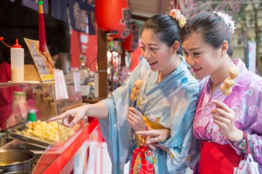 Asya genç bayanlar kızarmış köfte yanında sokak satıcısından satın alma. Onlar her ikisi de aç vardır. Başka bir kadın istediği lezzet işaret ediyor.