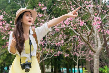 Kiraz ağacı altında duran ve öne doğru parmakla Asyalı Genç kız.