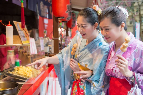 Asya genç bayanlar kızarmış köfte yanında sokak satıcısından satın alma. Onlar her ikisi de aç vardır. Başka bir kadın istediği lezzet işaret ediyor.